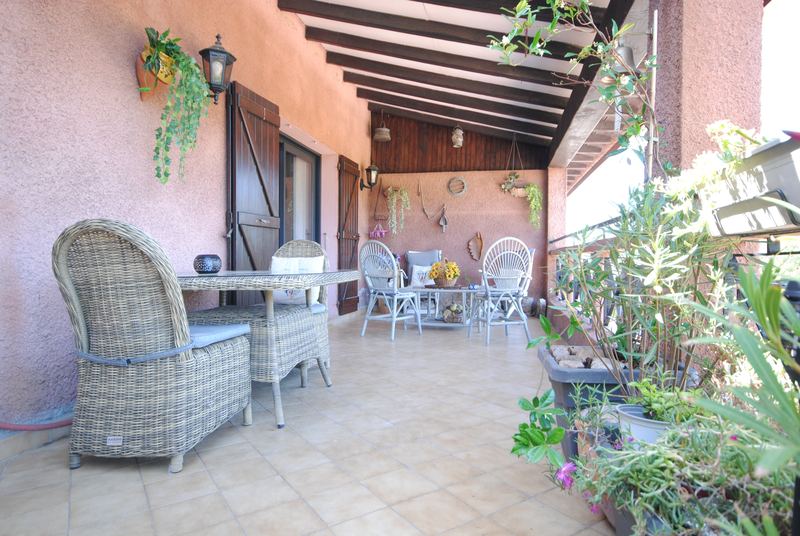 Terrasse couverte avec table et fauteuils en rotin